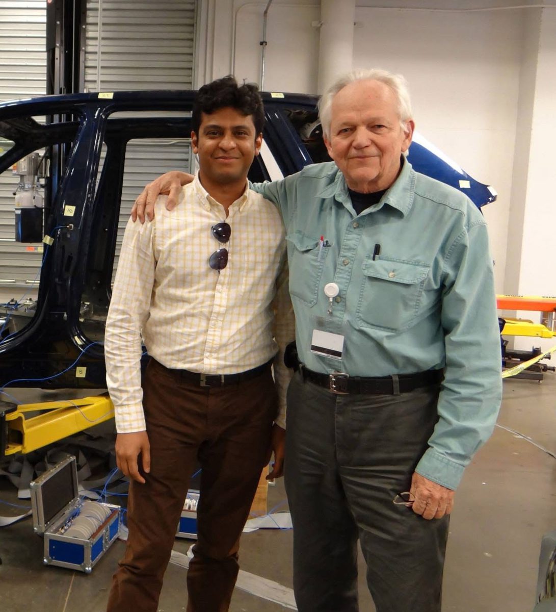 Hasan Pasha with Dr. David L. Brown in a vehicle test lab, a vehicle body behind them.